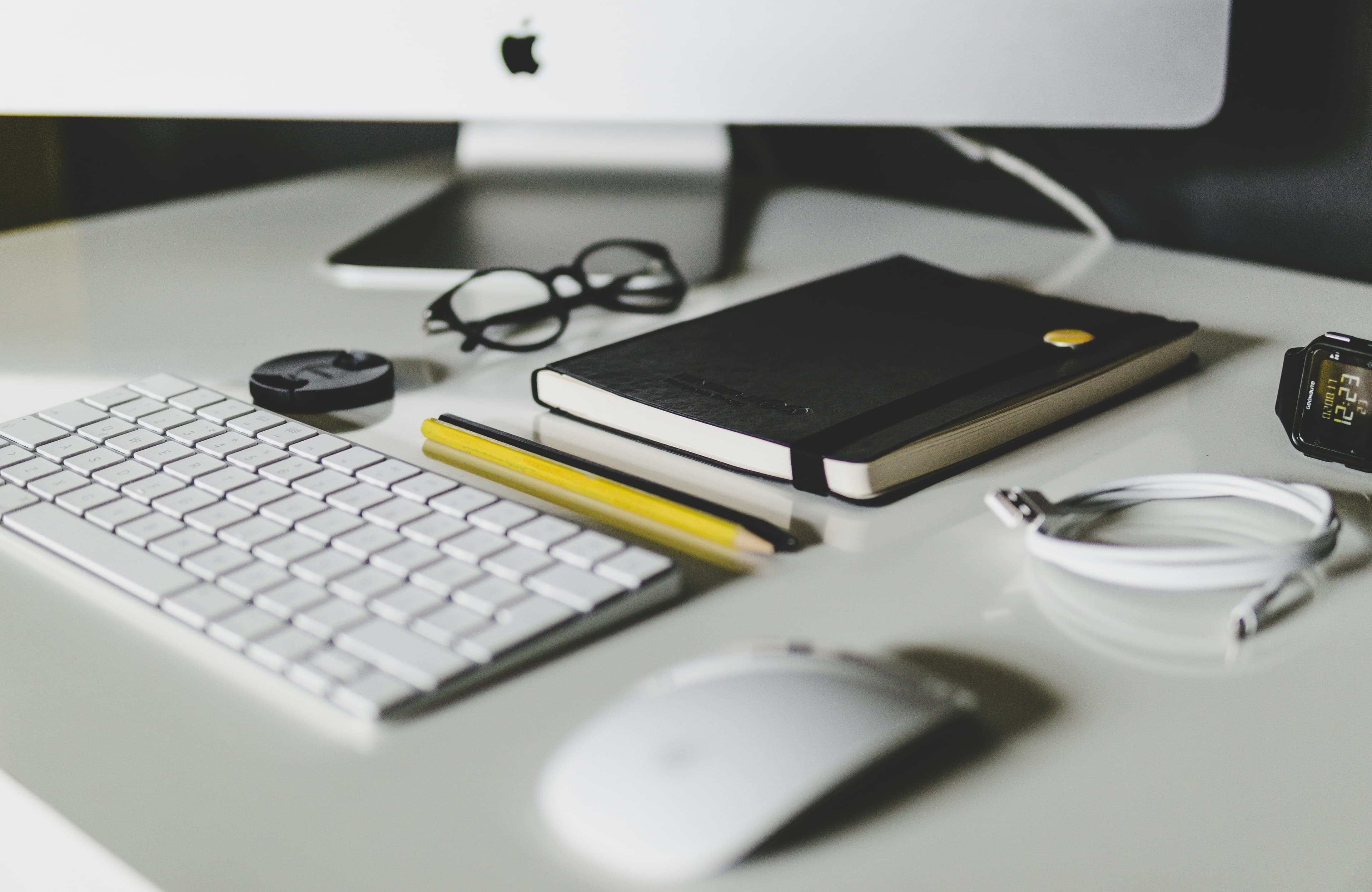 Desk accessories including keyboard, mouse, notebook, and watch